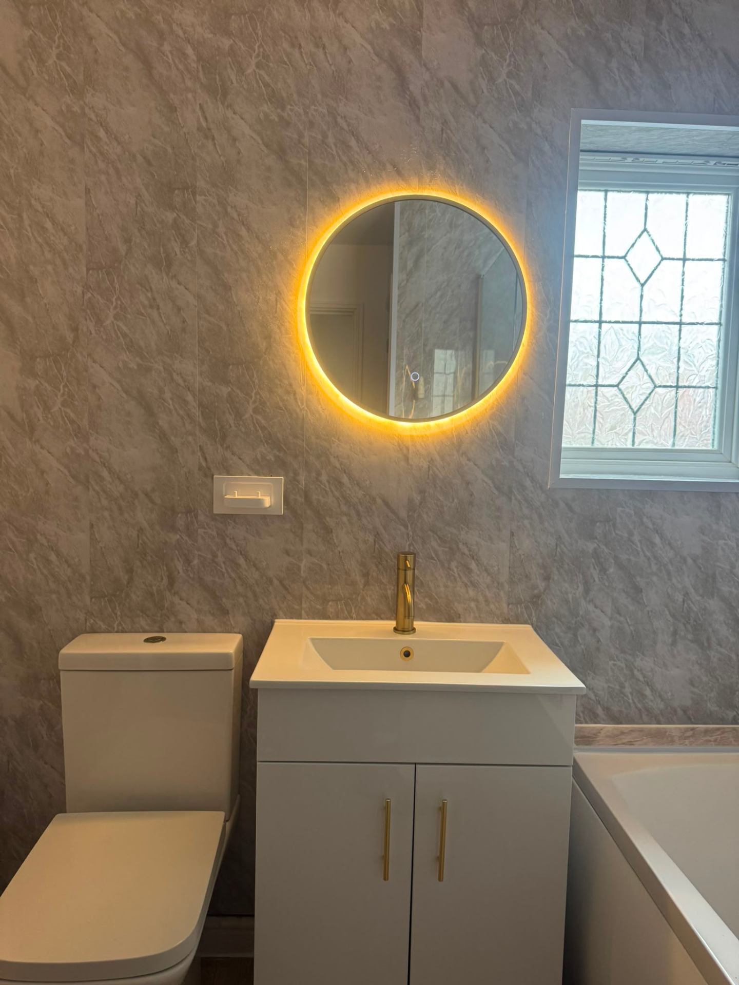 Compact ensuite with round mirror and grey-tiled walk-in shower